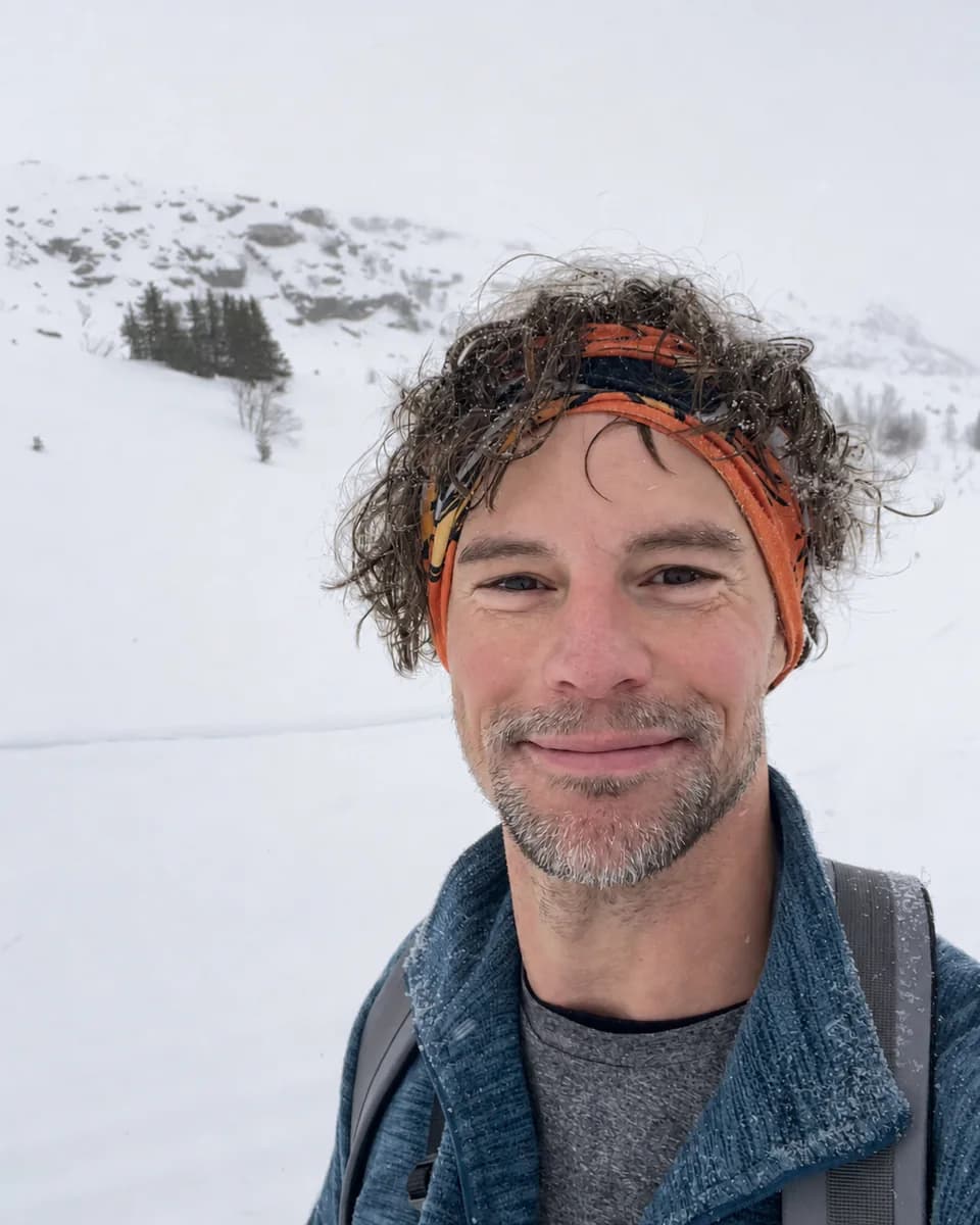 Tommy smiling at the camera in a snowy mountain landscape.